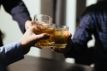 A group of businessmen held brandy glasses together to cheers glasses of brandy after concluding...