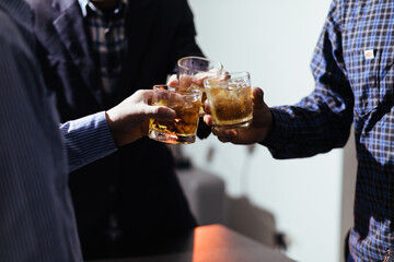 A group of businessmen held brandy glasses together to cheers glasses of brandy after concluding negotiations on business ventures and reaching a satisfactory agreement for joint business profits.