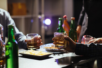A group of businessmen held brandy glasses together to cheers glasses of brandy after concluding negotiations on business ventures and reaching a satisfactory agreement for joint business profits.