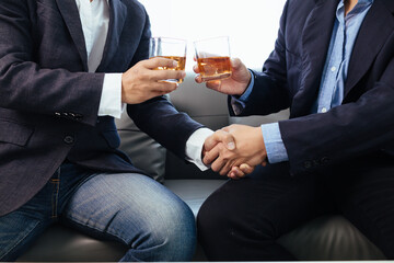 Businessmen and investors drink alcohol together in office after discussing their joint venture plans to conclusion. backdrop of alcoholic celebrations between investors and successful businessmen.