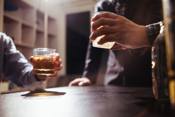 A group of businessmen held brandy glasses together to cheers glasses of brandy after concluding...