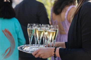 closeup of server holding silver tray of champagne glasses at summer wedding