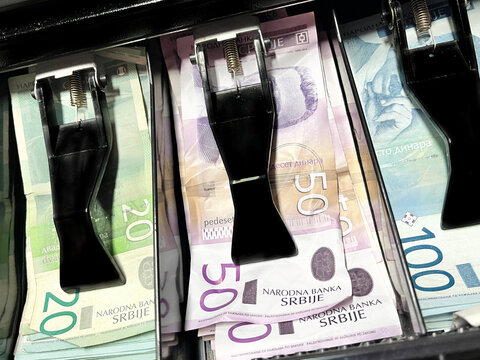 Cash notes secured under black clip mechanisms in a currency counting machine.