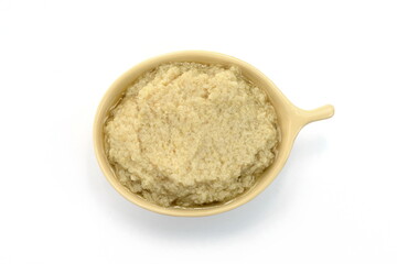 Top view of a small bowl filled with artichoke dip isolated on a white background. Artichoke spread, pesto.
