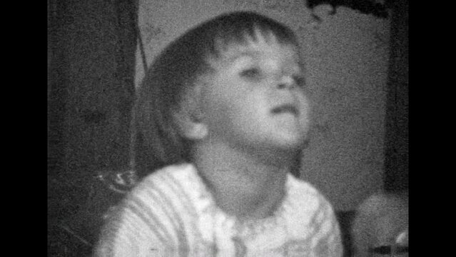 Archive film, active little girl jumping, having fun at home indoor. Healthy cheerful child playing near mother. Happy, hyperactive childhood. Vintage black white movie. Family retro 1980s lifestyle