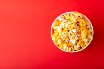 Popcorn box. Red and white striped buckets of popcorn on a red background. Cinema and entertainment concept. Movie night with popcorn. Cheesy popcorn. Delicious appetizer, snack. Place for text.