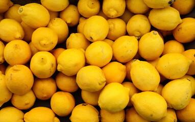 Colorful Display Of Lemons at fruit and vegetables street Market, organic ecological food from local producers. Ripe Yellow Lemons Close-up Background Or Texture. Lemon Harvest, Many Yellow Lemons.