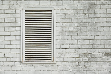Old gray brick wall with a window covered with iron blinds. Space for text. Background.