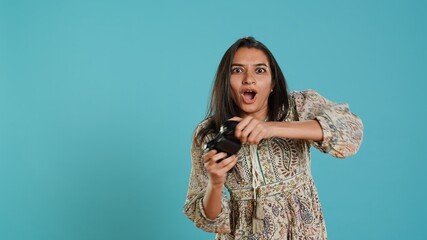 Competitive woman playing videogames with motion controlled controller, studio background. Indian...