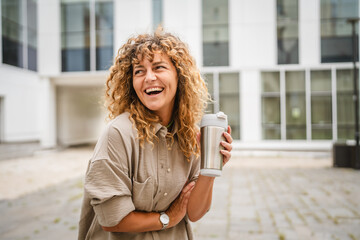 Portrait of woman stan in front business building and hold thermos cup