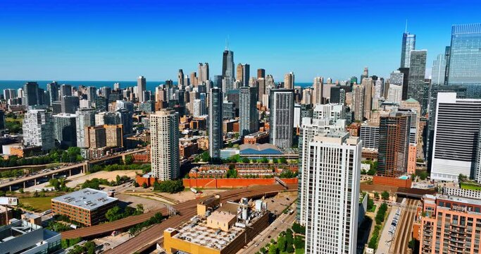 Beautiful cityscape of modern Chicago on clear sunny day. Drone footage above the buildings approaching the group of skyscrapers at backdrop.