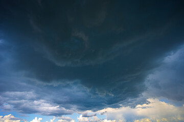 Dramatic storm clouds in blue sky associated with storm, dark, moody weather and looming atmosphere