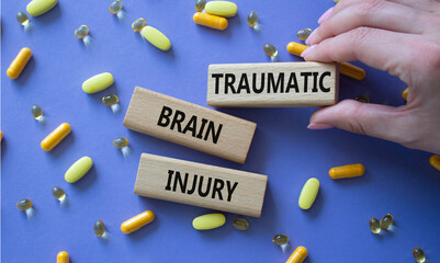 Traumatic Brain Injury symbol. Concept words Traumatic Brain Injury on wooden blocks. Beautiful purple background with pills. Doctor hand. Healthcare and Traumatic Brain Injury concept. Copy space.
