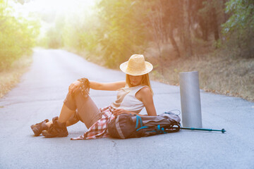 A traveler woman sits on the road.
