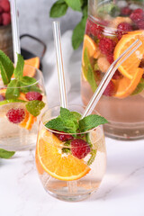 Summer Sangria cocktail or lemonade with raspberry, orange and mint. Refreshing organic non-alcoholic, Detox vitaminized healthy drink, fruit in a in a glass. Quench your thirst on a hot day.