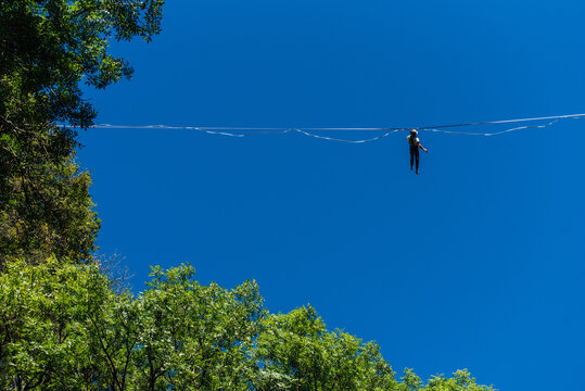un funambule dans la nature. Funambule en ext&eacute;rieur naturel. Acrobate sur un fil en hauteur. Funambule sur une corde tendue. Funambulisme dehors.. Equilibre