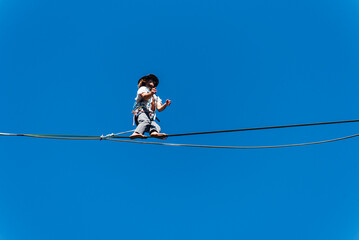 un funambule dans la nature. Funambule en ext&eacute;rieur naturel. Acrobate sur un fil en hauteur. Funambule sur une corde tendue. Funambulisme dehors.. Equilibre