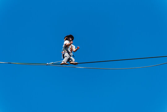 un funambule dans la nature. Funambule en extérieur naturel. Acrobate sur un fil en hauteur. Funambule sur une corde tendue. Funambulisme dehors.. Equilibre