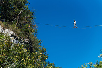 un funambule dans la nature. Funambule en extérieur naturel. Acrobate sur un fil en hauteur. Funambule sur une corde tendue. Funambulisme dehors.. Equilibre © david