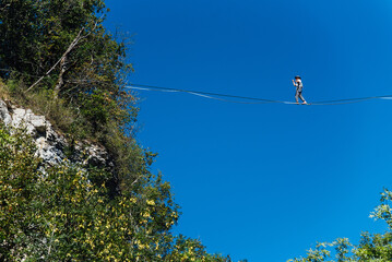 un funambule dans la nature. Funambule en extérieur naturel. Acrobate sur un fil en hauteur. Funambule sur une corde tendue. Funambulisme dehors.. Equilibre © david