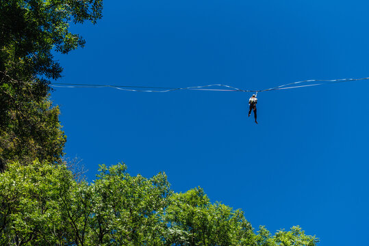 un funambule dans la nature. Funambule en ext&eacute;rieur naturel. Acrobate sur un fil en hauteur. Funambule sur une corde tendue. Funambulisme dehors.. Equilibre