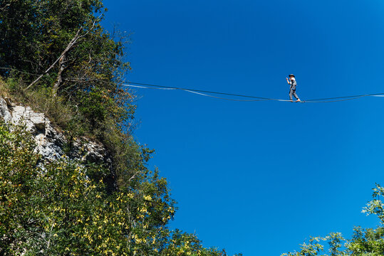 un funambule dans la nature. Funambule en extérieur naturel. Acrobate sur un fil en hauteur. Funambule sur une corde tendue. Funambulisme dehors.. Equilibre