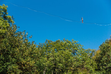 un funambule dans la nature. Funambule en extérieur naturel. Acrobate sur un fil en hauteur. Funambule sur une corde tendue. Funambulisme dehors.. Equilibre