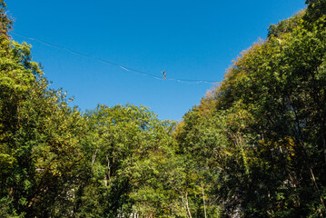 un funambule dans la nature. Funambule en extérieur naturel. Acrobate sur un fil en hauteur. Funambule sur une corde tendue. Funambulisme dehors.. Equilibre