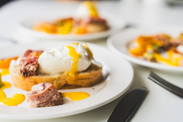 Plates of toast with egg benedict, tuna and hollandaise sauce on a white background. Selected focus.