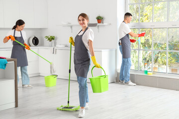 Team of young janitors cleaning in kitchen