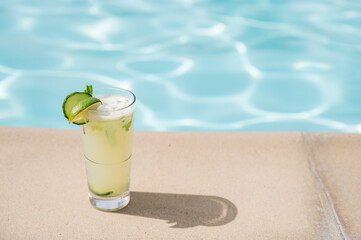 Color photo of a mint mojito sitting on the side of a pool, dramatic shadow - summer resort vacation