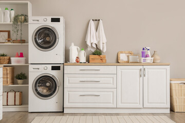 Interior of modern laundry room with washing machines and cleaning supplies