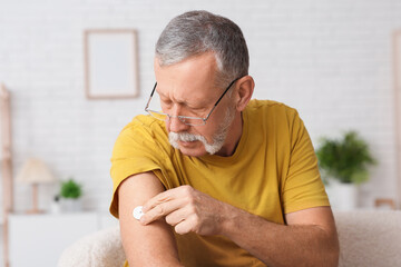Senior man with glucose sensor for measuring blood sugar level at home. Diabetes concept