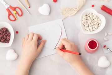 Child makes paper heart filled with haricot beans coloured in red love symbol preschool activity