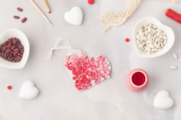 Child makes paper heart filled with haricot beans coloured in red love symbol preschool activity