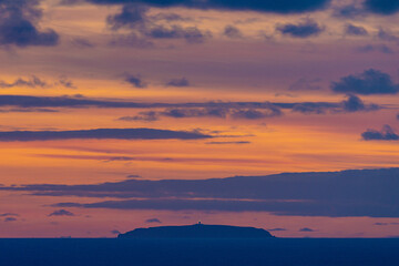 Distant island silhouette at colorful sunset, Nazaré, Portugal