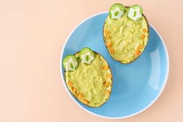 Healthy tasty snack for kids. Creamy avocado dip in the form of crocodile on blue ceramic plate..