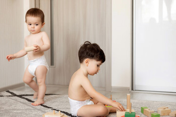 baby boy infant and kid playing in room with wooden toys blocks, train,cars.sibling, brothers or...