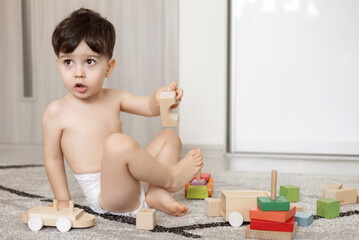 baby boy infant and kid playing in room with wooden toys blocks, train,cars.sibling, brothers or...