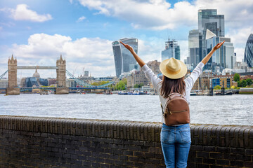 A happy tourist woman on a sightseeing trip looks at the skyline of London, England, during a sunny...