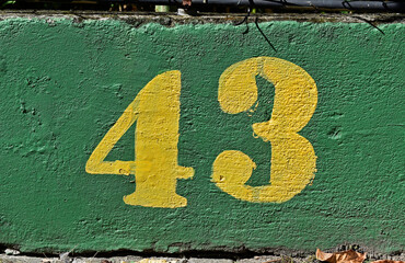 Number 43 painted in yellow on a green wall