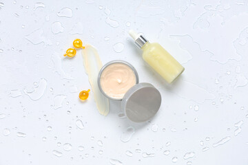 Jar of hair mask with bottle of cosmetic product, capsules and water on white background