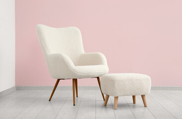 White armchair and pouf near pink wall