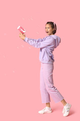 Teenage girl with soap bubble gun on pink background