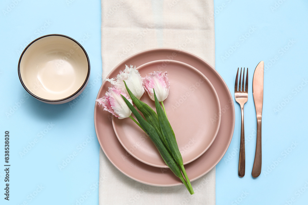 Wall mural stylish table setting with beautiful tulips on blue background