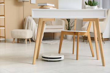 Modern robot vacuum cleaner under table at home