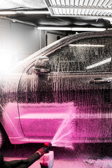 Washing a car using pink detergent at a self service car wash. The process of applying pink foam to...