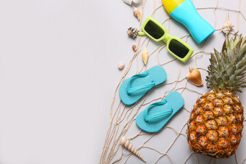 Beautiful seashells, flip-flops, pineapple, sunscreen cream and sunglasses on orange background....