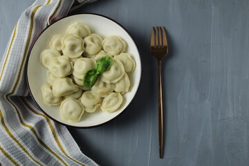 Serving lunch dumplings in a bowl with napkin, towel, fork, top view on gray background with space for copyspace text