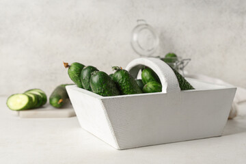 Basket with fresh green cucumbers on white background